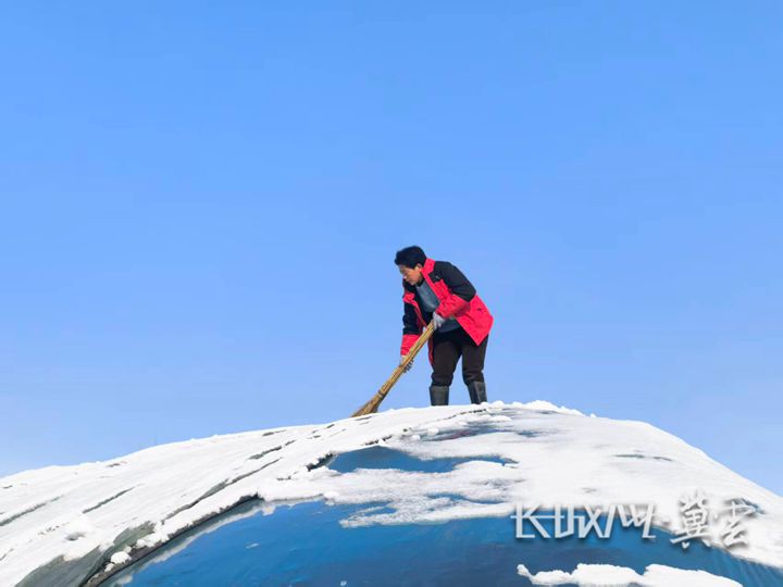 12月13日,農戶楊國翠正在自家蔬菜大棚上清理棚頂積雪。長城網·冀云客戶端訊記者 楊蕾 攝